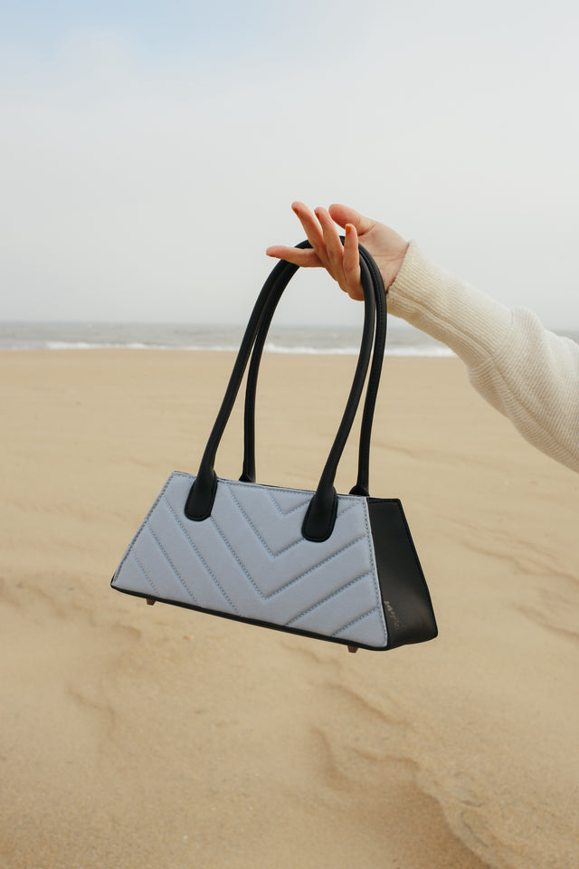 Blue organic cotton shoulder purse with black cactus leather shown on the beach in Asbury Park, NJ